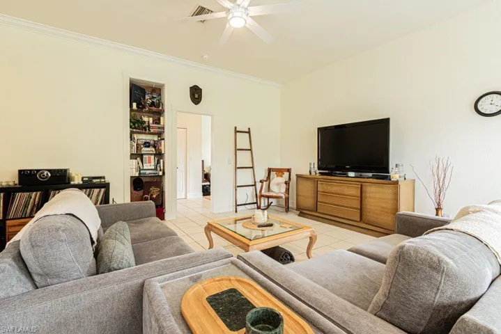 Living area featuring tile patterned floors, a ceiling fan, and ornamental molding