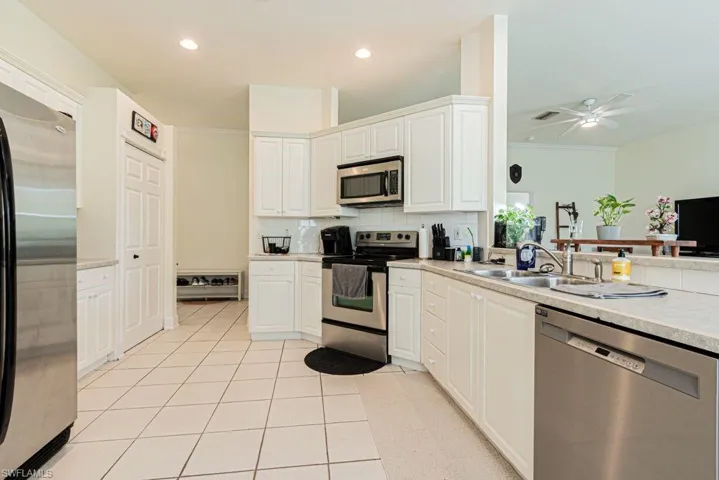 Kitchen featuring appliances with stainless steel finishes, tasteful backsplash, light countertops, white cabinets, and recessed lighting