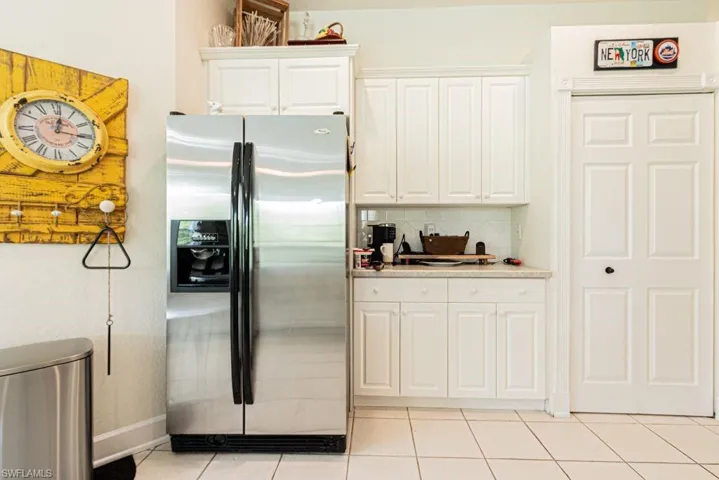 Kitchen featuring stainless steel refrigerator with ice dispenser, white cabinets, tasteful backsplash, light countertops, and light tile patterned floors