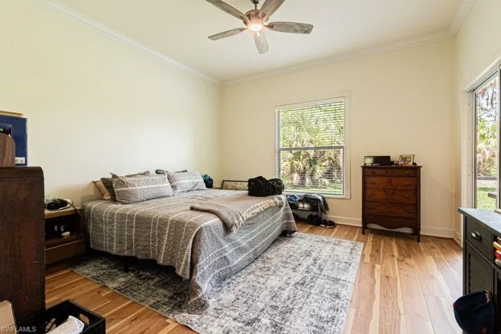 Bedroom with crown molding, light wood-type flooring, and a ceiling fan