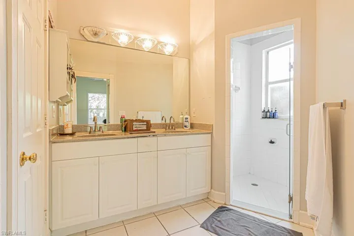 Bathroom with double vanity, a stall shower, and tile patterned floors
