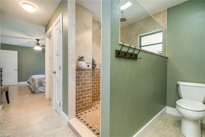 Ensuite bathroom featuring ensuite bath, a ceiling fan, walk in shower, and toilet