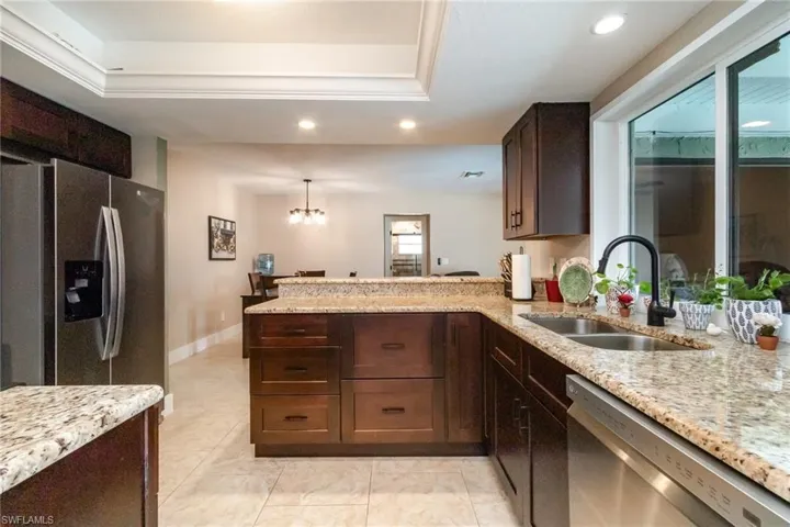 Kitchen featuring a sink, appliances with stainless steel finishes, a peninsula, recessed lighting, and light stone counters