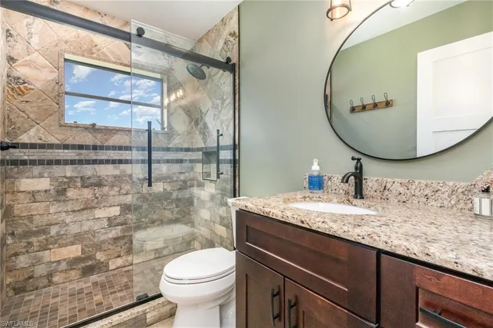 Full bath featuring toilet, a stall shower, and vanity