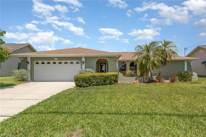 View of front of property featuring an attached garage, stucco siding, a front lawn, and concrete driveway
