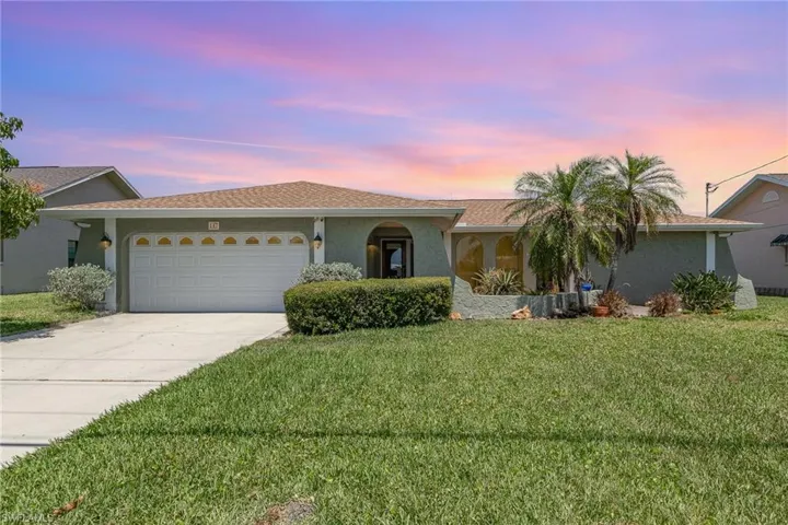 Ranch-style house with a yard, an attached garage, stucco siding, and concrete driveway