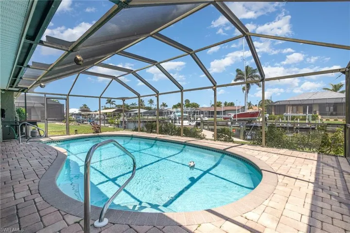 Outdoor pool featuring a dock, a residential view, glass enclosure, and a patio