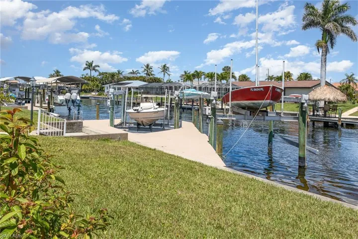 View of dock featuring a water view, a lawn, and boat lift