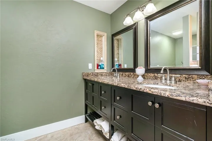 Full bath with double vanity, a sink, and baseboards