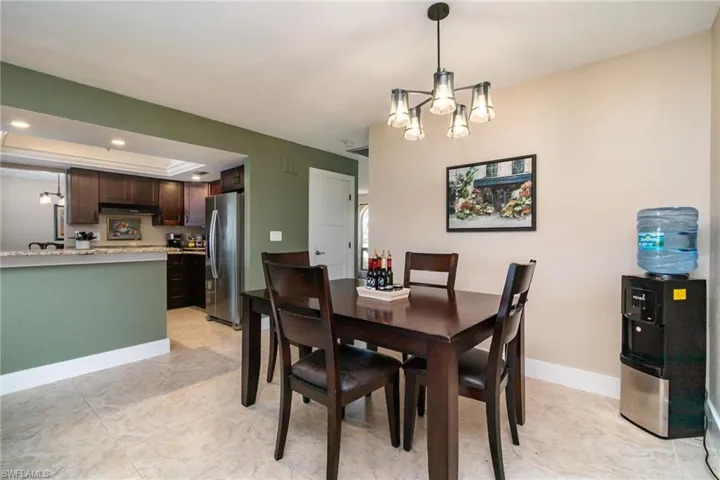 Dining space featuring baseboards, an inviting chandelier, a tray ceiling, recessed lighting, and light tile patterned flooring