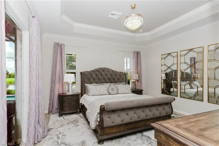 Tray ceiling with crown molding, crystal chandelier, and large sliding glass door