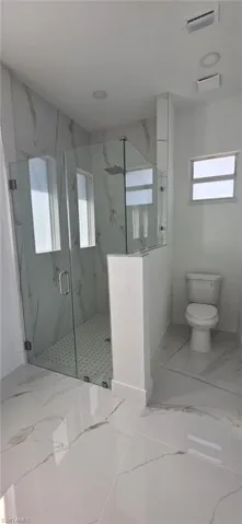 Bathroom featuring a marble finish shower and light marble finish flooring