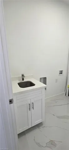Laundry room with cabinet space, washer hookup, and light marble finish flooring