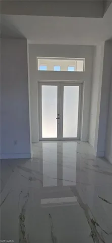 Empty room featuring light marble finish flooring and baseboards