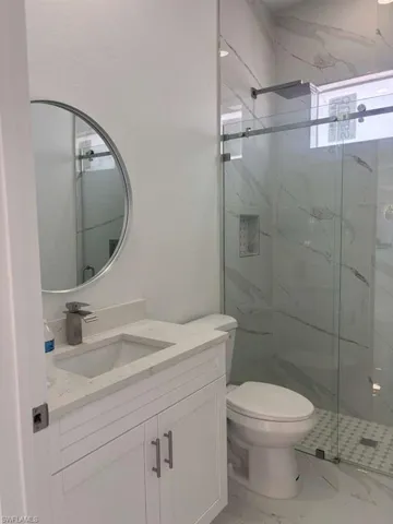 Full bath with vanity, a marble finish shower, and marble finish floors