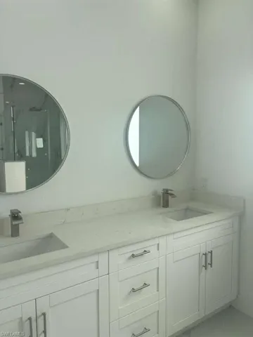 Full bath featuring double vanity and a marble finish shower