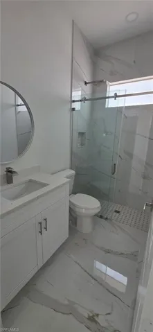 Full bath with vanity, a marble finish shower, and light marble finish floors