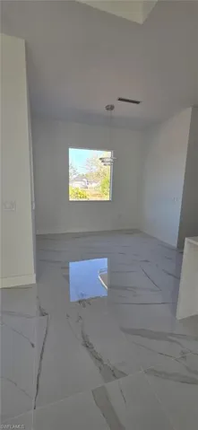 Empty room featuring light marble finish flooring and hanging lights