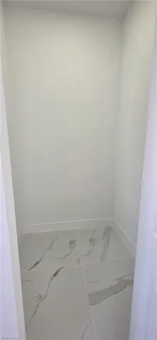 Bathroom featuring baseboards and light marble finish flooring