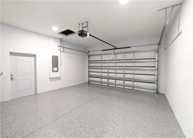 Garage featuring a garage door opener, epoxy floors, and electric panel