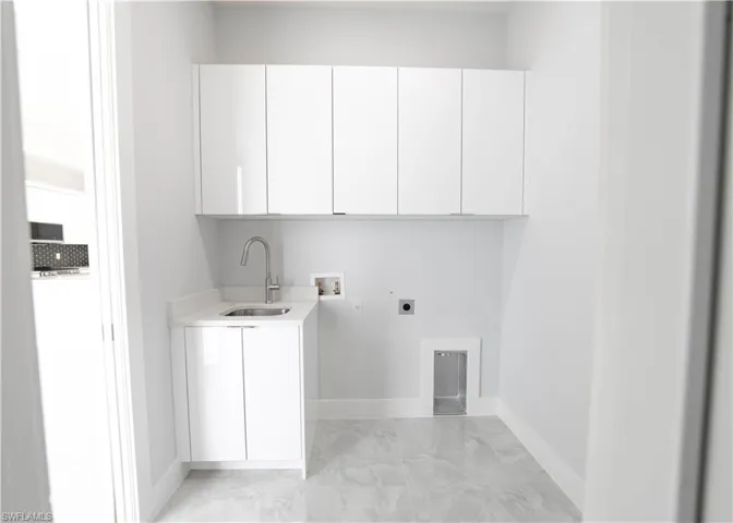 Clothes washing area featuring hookup for an electric dryer, sink, washer hookup, and cabinets