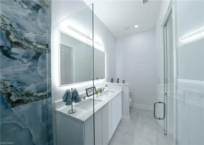 Bathroom with vanity, toilet, and an enclosed shower