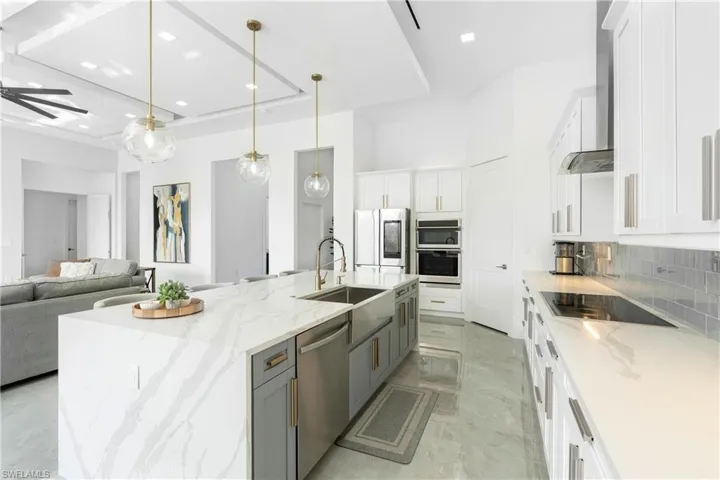 Kitchen with white cabinetry, a large island, stainless steel appliances, and light stone counters