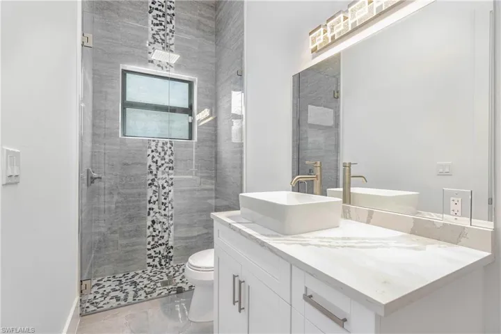Bathroom featuring vanity, a shower with shower door, and toilet