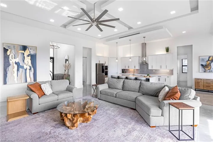 Living room with a towering ceiling, a raised ceiling, ceiling fan, and sink