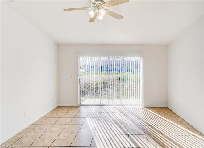 Empty room with light tile patterned floors and a ceiling fan