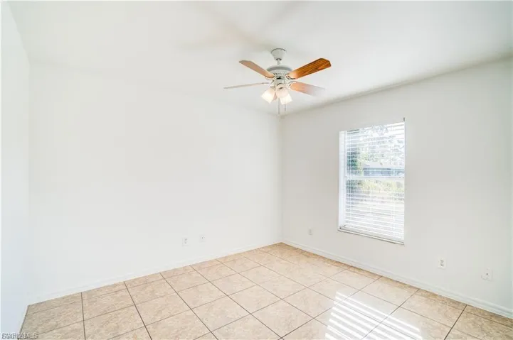 Empty room with light tile patterned flooring and a ceiling fan