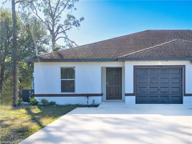 View of front of property featuring a garage, stucco siding, and concrete driveway