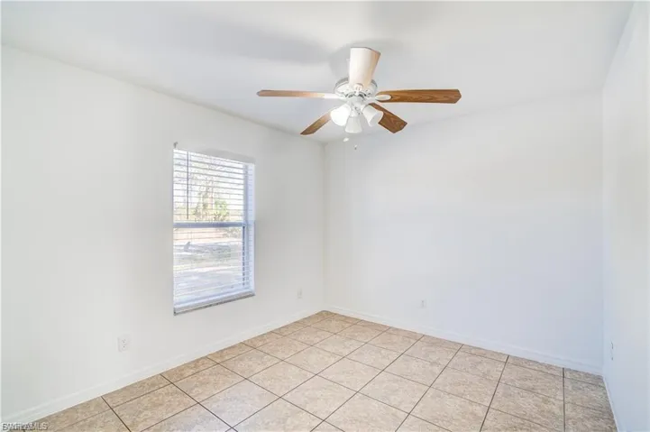 Empty room with a ceiling fan and light tile patterned floors