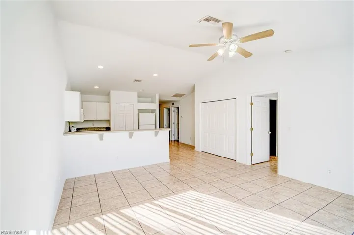 Unfurnished living room featuring light tile patterned floors, lofted ceiling, ceiling fan, and recessed lighting