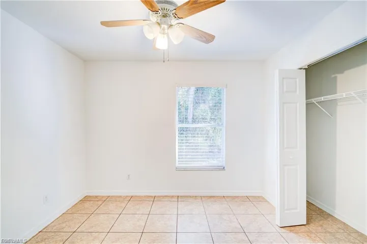 Unfurnished bedroom featuring a closet, ceiling fan, and light tile patterned flooring