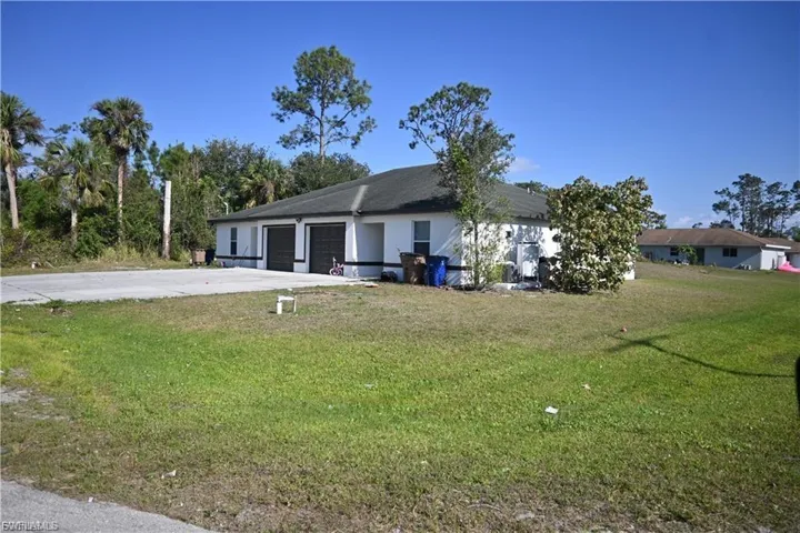 View of front of home featuring a front lawn, concrete driveway, a garage, a patio, and stucco siding