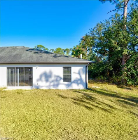 Rear view of house featuring stucco siding and a yard