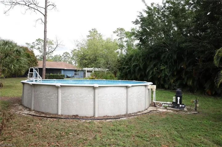 Swimming pool with a yard and view of scattered trees