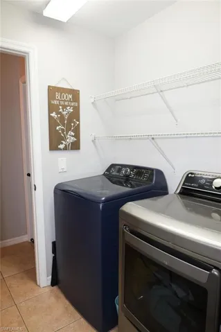 Laundry room with washer and clothes dryer and light tile patterned floors