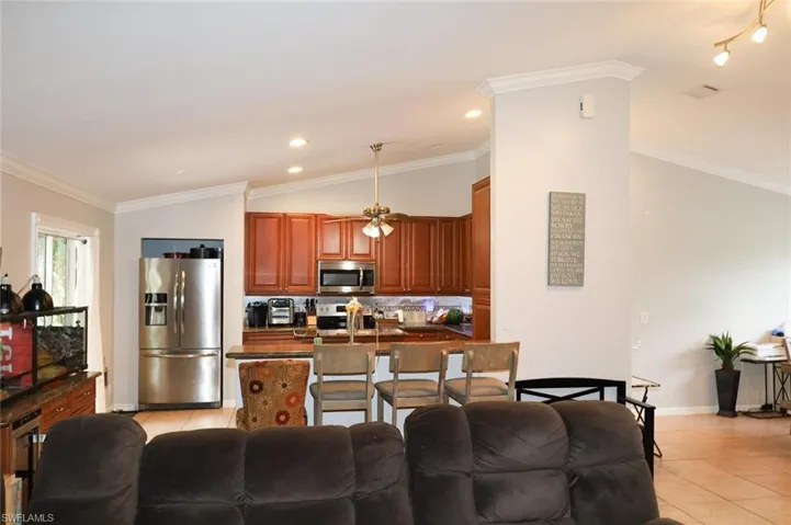 Living room with ornamental molding, light tile patterned floors, vaulted ceiling, and recessed lighting