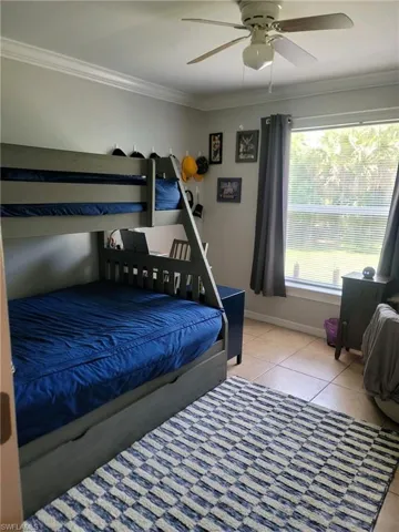 Bedroom featuring ornamental molding, light tile patterned floors, and ceiling fan
