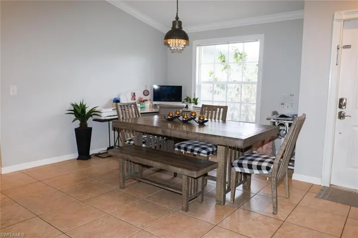 Dining space with light tile patterned floors and ornamental molding
