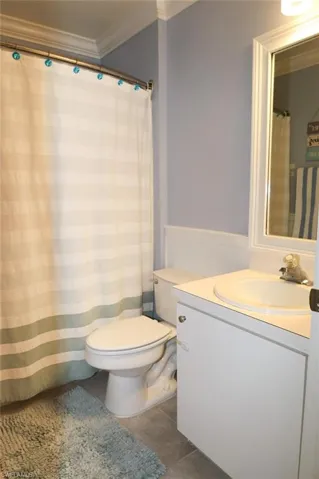 Bathroom with ornamental molding, vanity, tile patterned flooring, and curtained shower