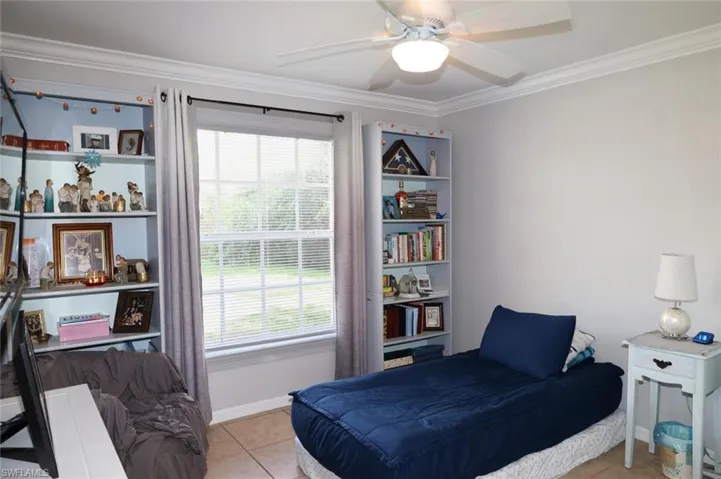 Bedroom featuring crown molding, light tile patterned floors, and ceiling fan