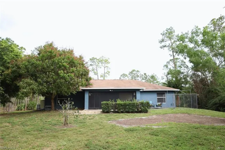 Rear view of house with a yard, a sunroom, and stucco siding