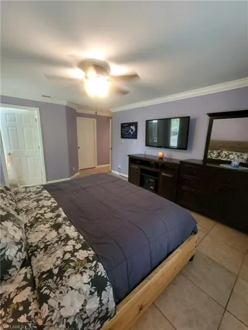 Bedroom featuring ornamental molding, light tile patterned flooring, and ceiling fan