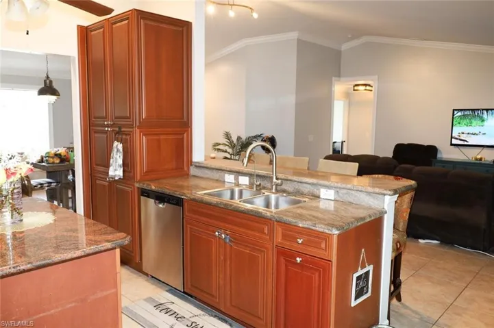 Kitchen featuring a peninsula, crown molding, a breakfast bar area, brown cabinets, and dark stone countertops