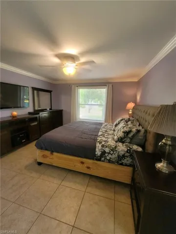 Bedroom with crown molding, light tile patterned floors, and ceiling fan