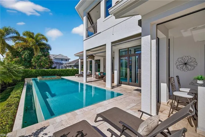 Rectangular swimming pool with an integrated spa, surrounded by travertine-style patio pavers