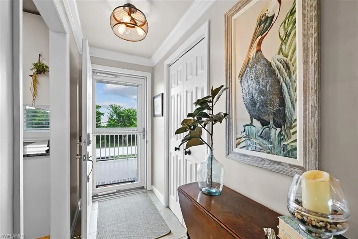 Doorway to outside featuring tile patterned floors and crown molding